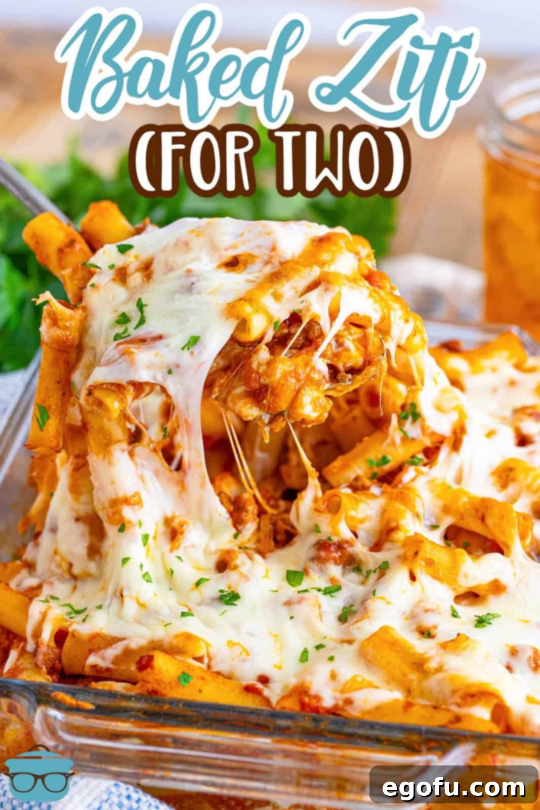 A serving utensil getting a large serving of Baked Ziti for Two out of a baking dish.