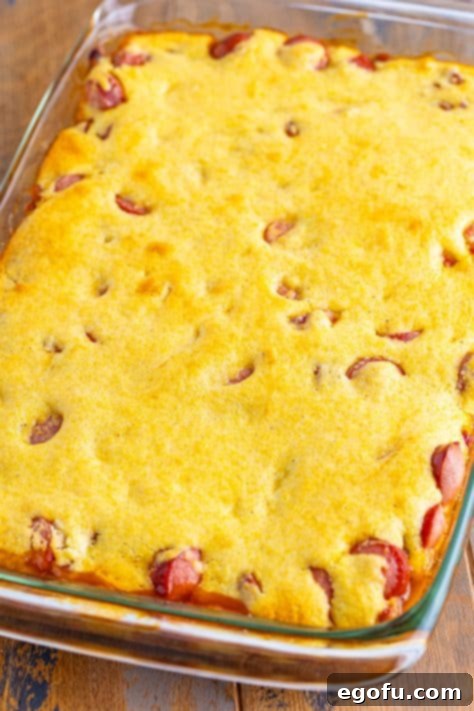 Baked beans, hot dogs, and cornbread mixture in a casserole dish.