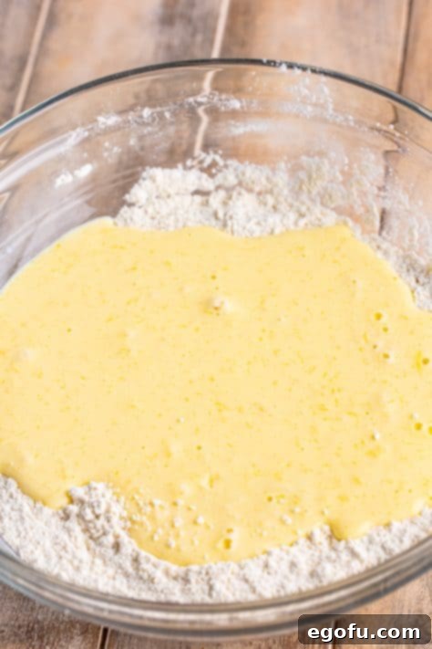 Wet ingredients being added to the dry ingredients to make Buttermilk Waffles batter.