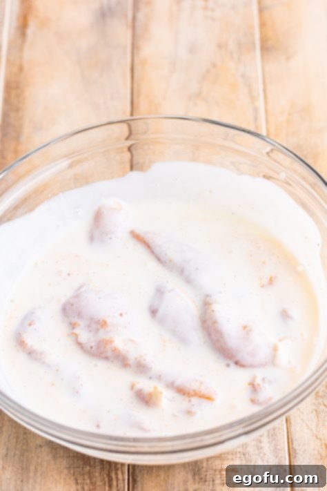 Chicken tenders covered in buttermilk, hot sauce, salt, garlic powder, onion powder, paprika, and pepper.