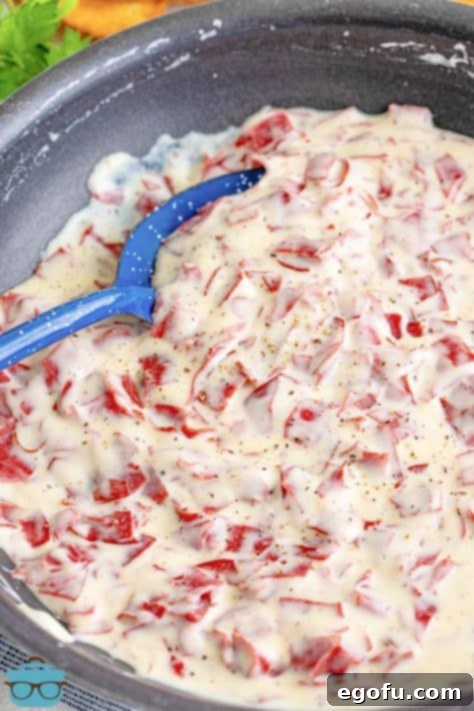 A serving utensil stirring some Creamed Chip Beef in a saucepan.