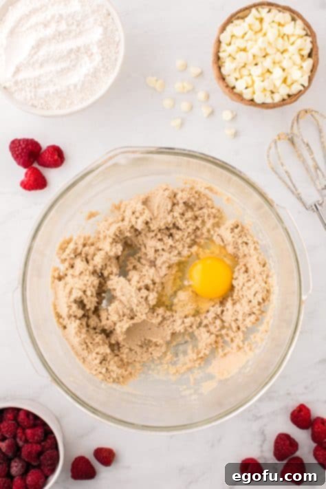 A mixing bowl with brown sugar, white sugar, and egg.