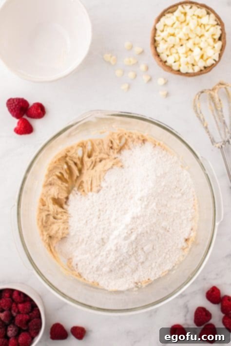 Flour on top of the wet cookie dough ingredients.
