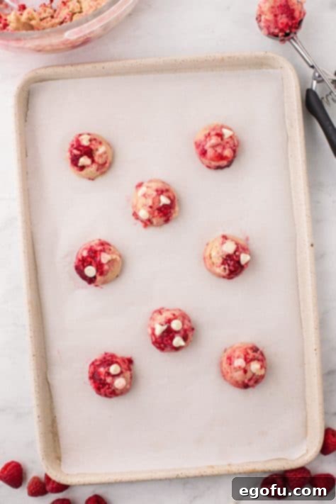 Raw Raspberry White Chocolate Chip Cookies on a lined baking sheet.