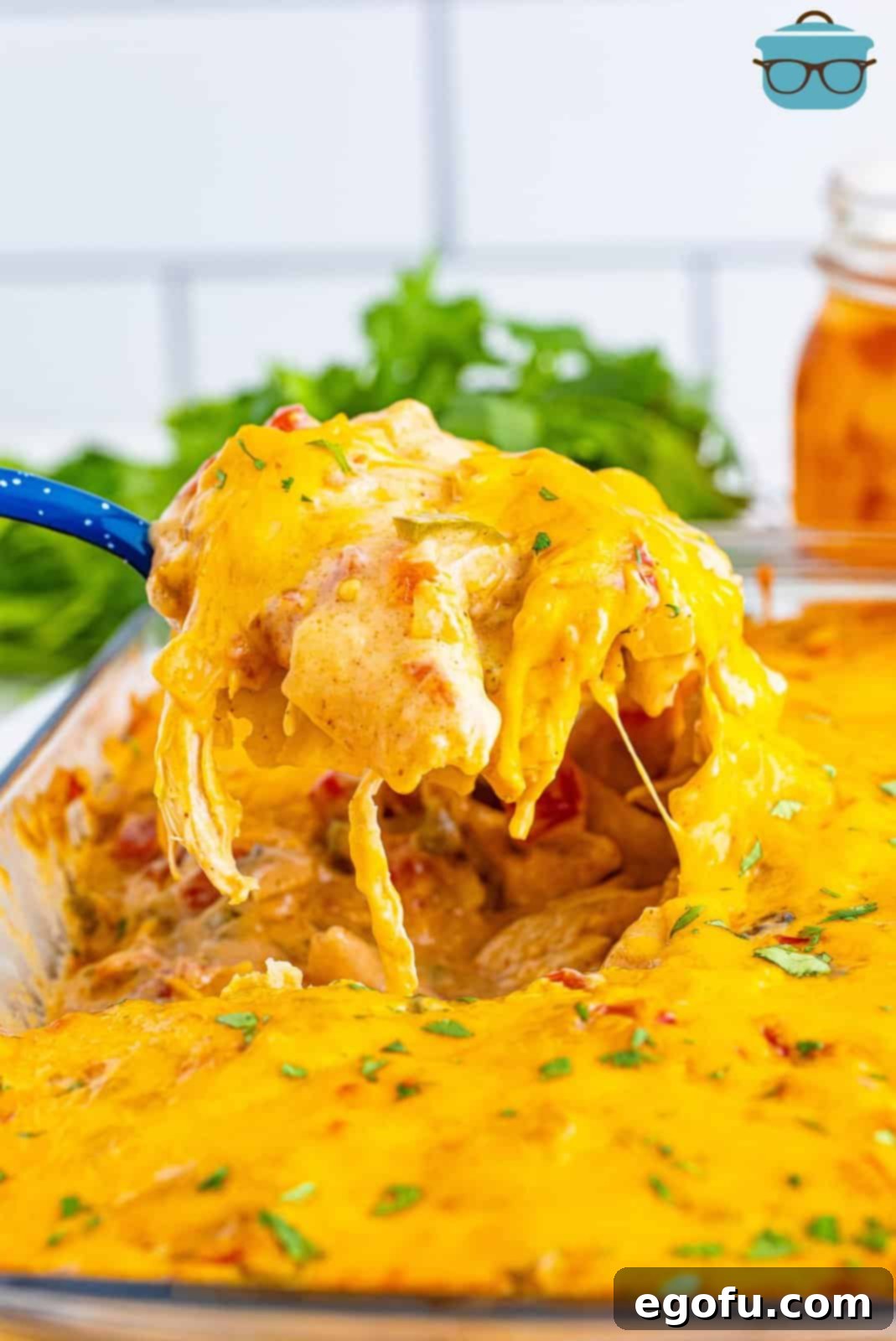 A serving of King Ranch Chicken Casserole being held above the baking dish. 