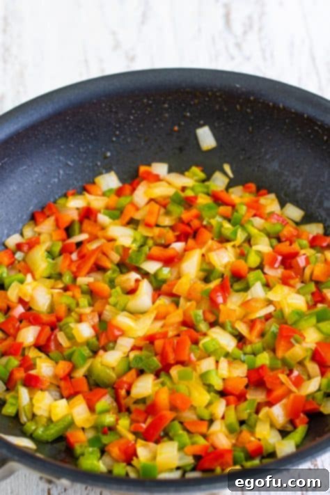 A skillet with melted butter, onion, green bell pepper, and red bell pepper.