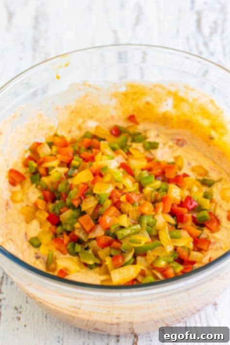 A bowl with diced tomatoes, cream of chicken soup, cream of mushroom soup, chopped green chiles, chicken stock, sour cream, chili powder, garlic powder, cumin, and onion powder and cooked veggies.