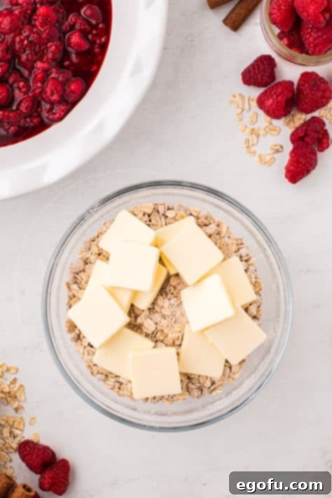 Slices of cold butter on top of crumble ingredients in a mixing bowl.
