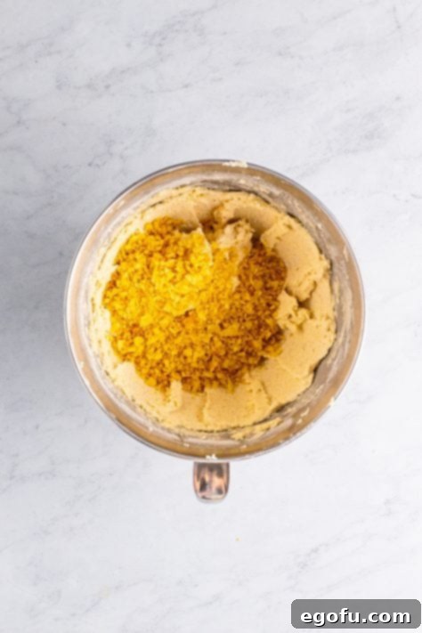 Crushed potato chips being added to a cookie dough mix.