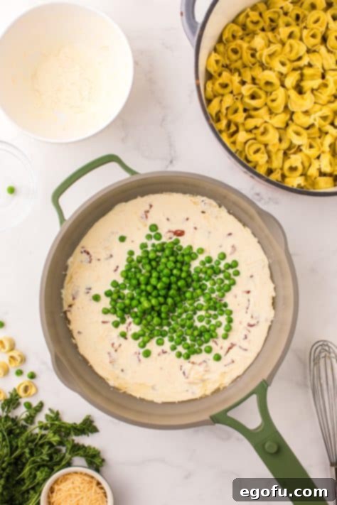 Peas and a cream sauce in a skillet.