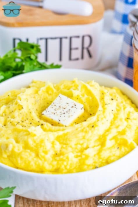Velvety Stovetop Mashed Potatoes 11 A large bowl of golden Stovetop mashed potatoes with a generous pat of butter melting on top, perfectly ready to be served and enjoyed.