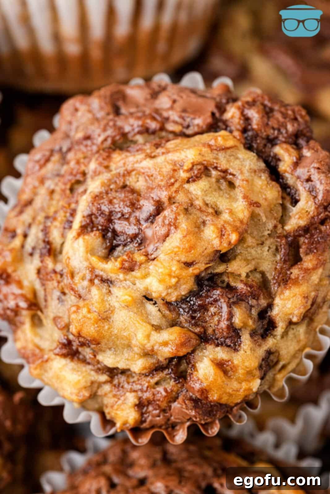 A top-down view of beautifully baked Nutella Swirl Banana Muffins, showing off the rich, marbled chocolate hazelnut swirls on a tender banana base.