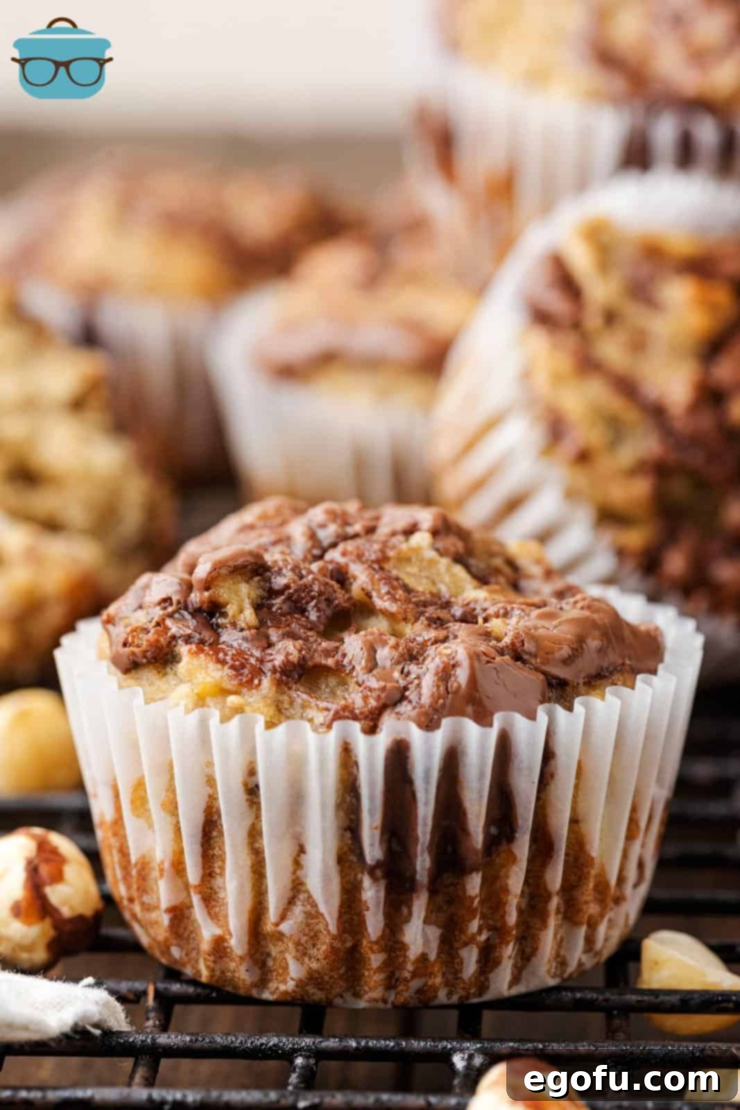 A few tempting Nutella Swirl Banana Muffins resting on a cooling rack, still in their festive wrappers, ready for enjoyment.