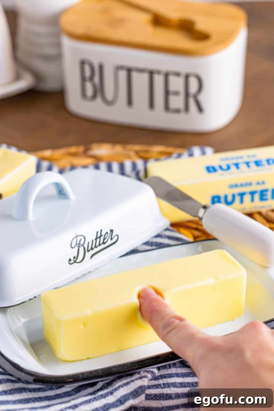 A finger pressing on a stick of soft butter, showing the ideal consistency.