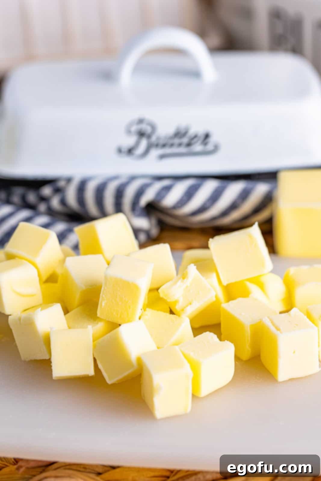 Cubed up pieces of butter spread out on a plate to soften faster.