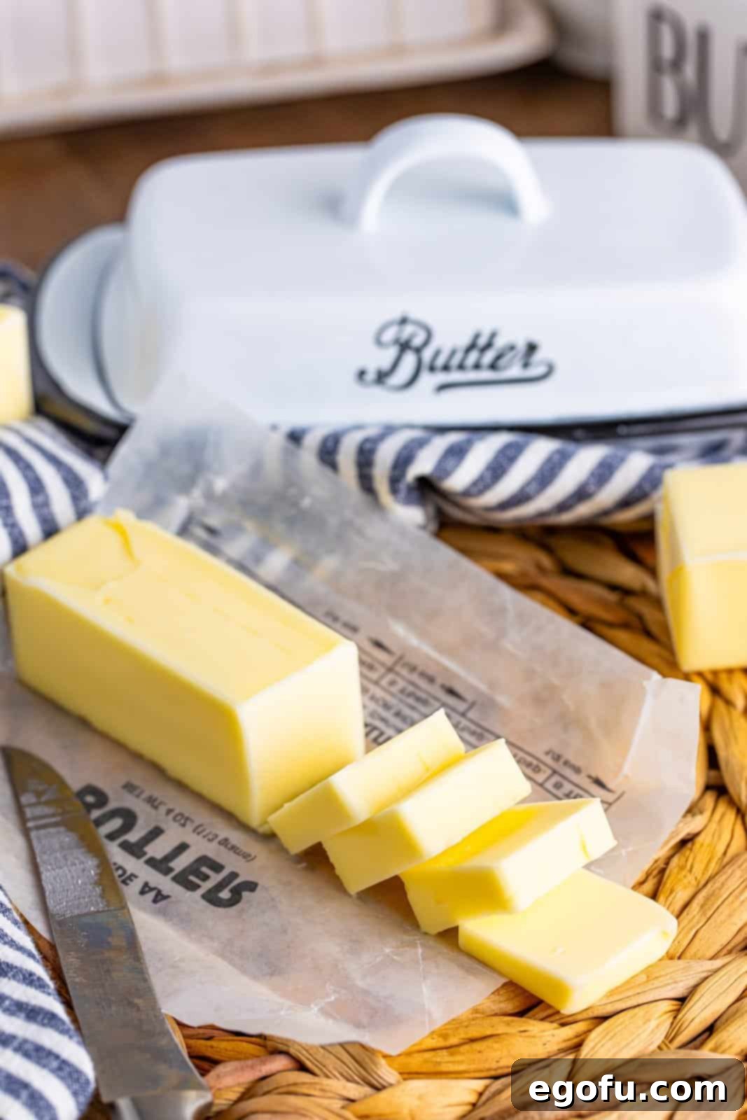 A stick of butter sliced into a few thin pats on a plate.