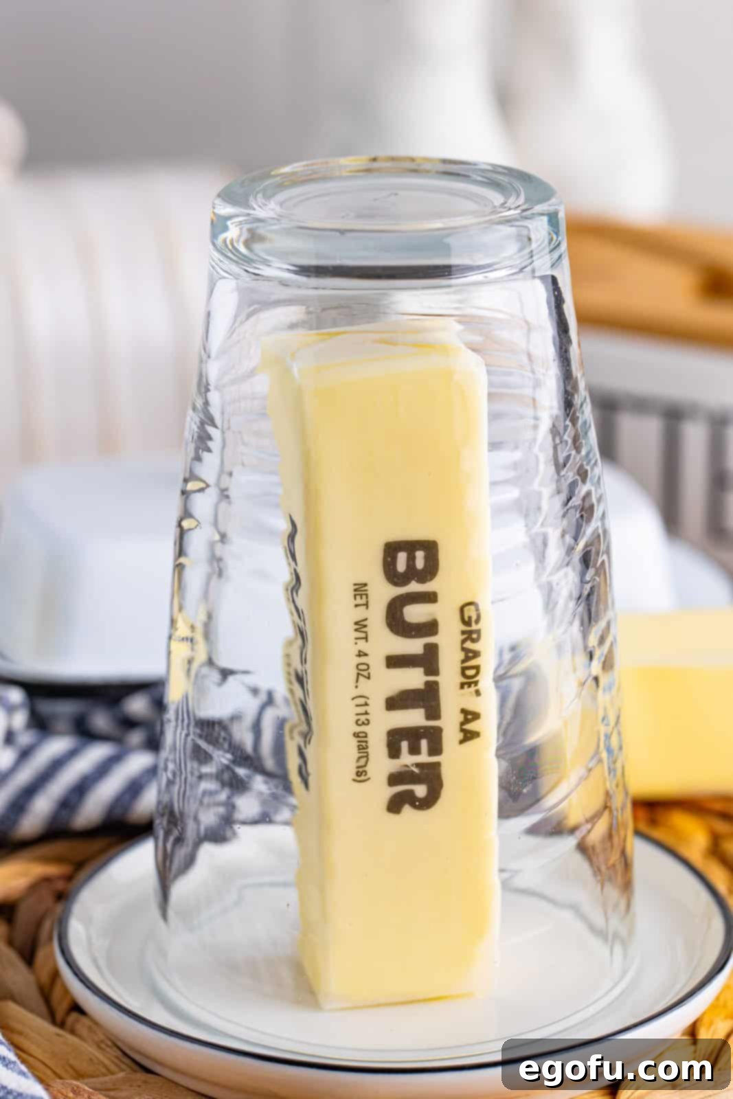 A warm glass inverted over a stick of butter on a plate, demonstrating the hot water glass method.