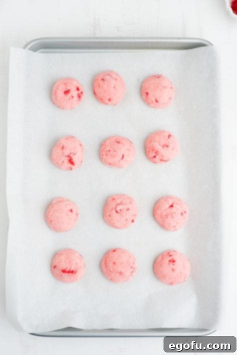 Sakura Bloom Bites 15 Baked Cherry Blossom Cookies waiting on Hershey Kisses on a piece of parchment paper.