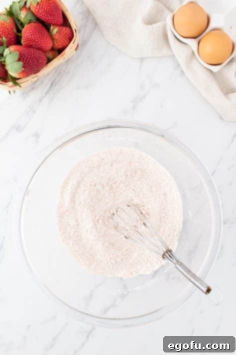 Decadent Strawberry Cake Bites 12 A glass mixing bowl with flour, baking powder, salt, and strawberry jello powder.