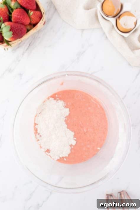 Decadent Strawberry Cake Bites 14 Dry and wet ingredients for Strawberry Cake Balls being mixed together in a bowl.