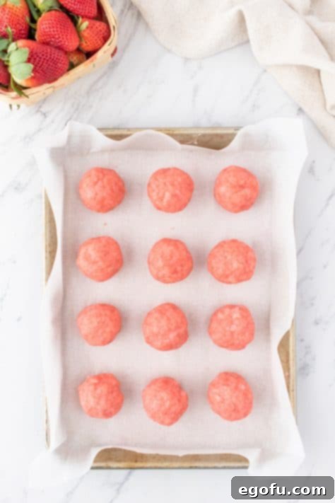 Decadent Strawberry Cake Bites 18 Strawberry Cake Balls on parchment lined baking sheet.