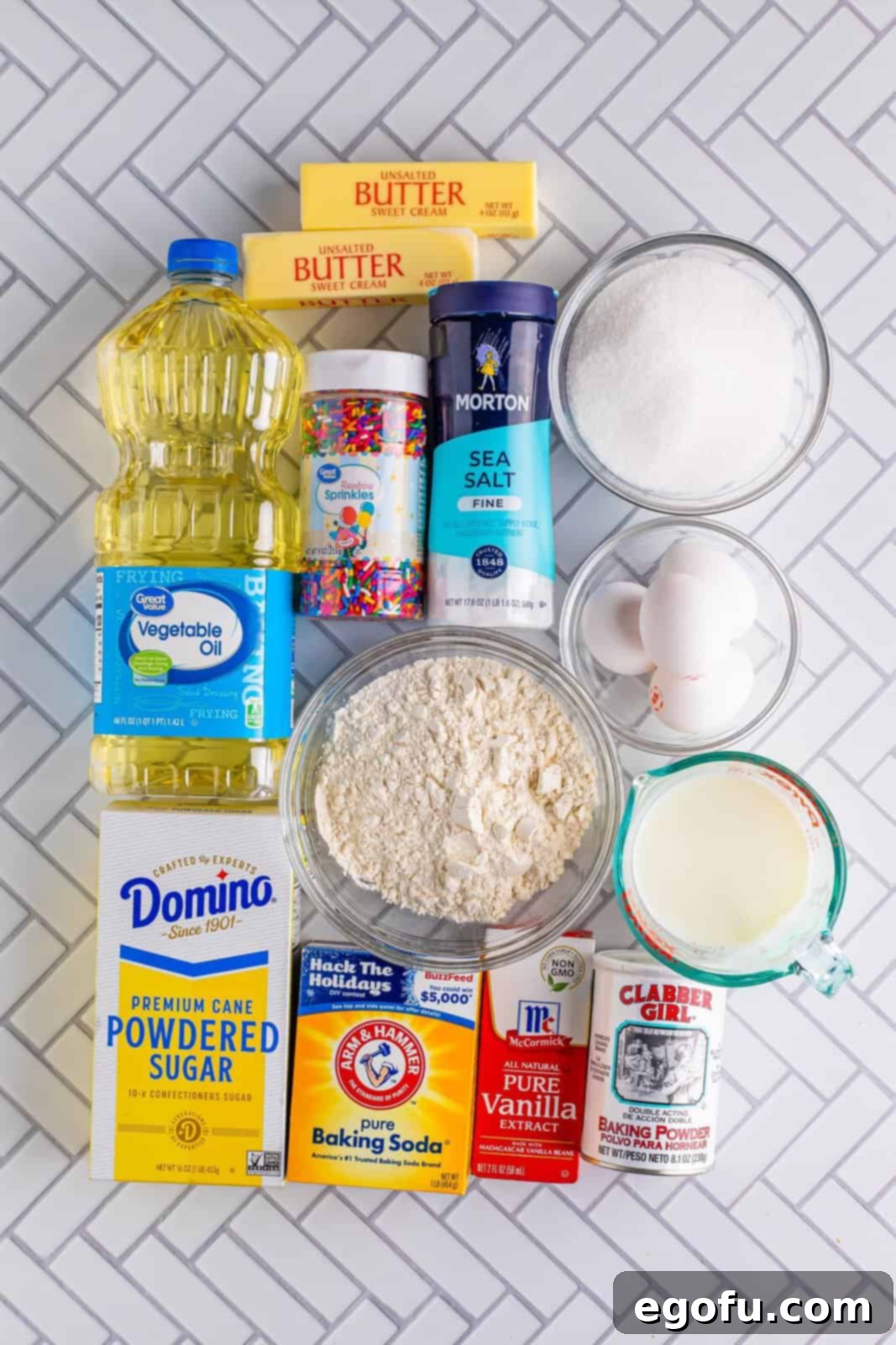 Festive Confetti Cupcakes 4 An array of fresh, quality ingredients meticulously laid out on a clean surface: all-purpose flour, granulated sugar, baking powder, baking soda, large egg whites, vanilla extract, whole milk, vegetable oil, vibrant rainbow sprinkles, softened unsalted butter, powdered sugar, and fine sea salt, all ready for the exciting preparation of homemade Funfetti Cupcakes.