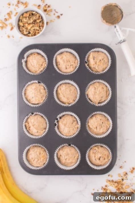 Banana Nut Cake Mix Muffin batter in cupcake liners in each of the muffin tin wells.