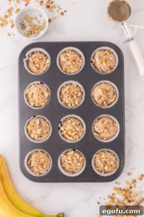 Chopped walnuts on top of the muffin batter in the muffin tin wells.
