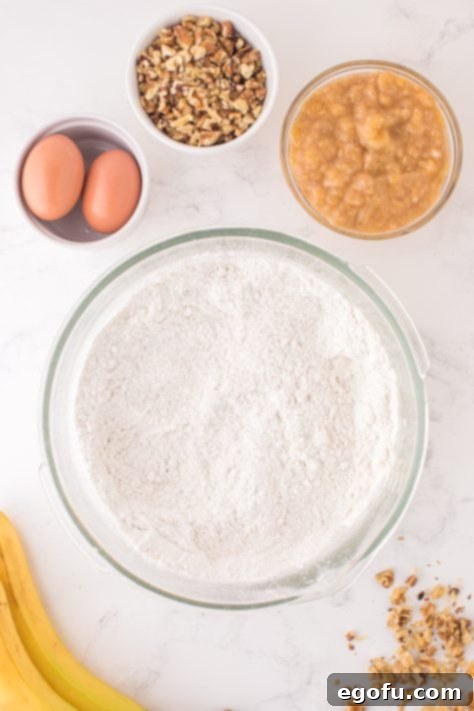 A large glass mixing bowl with cake mix, flour and baking powder.