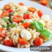 A bowl of fresh made Caprese Pasta Salad, garnished with basil.