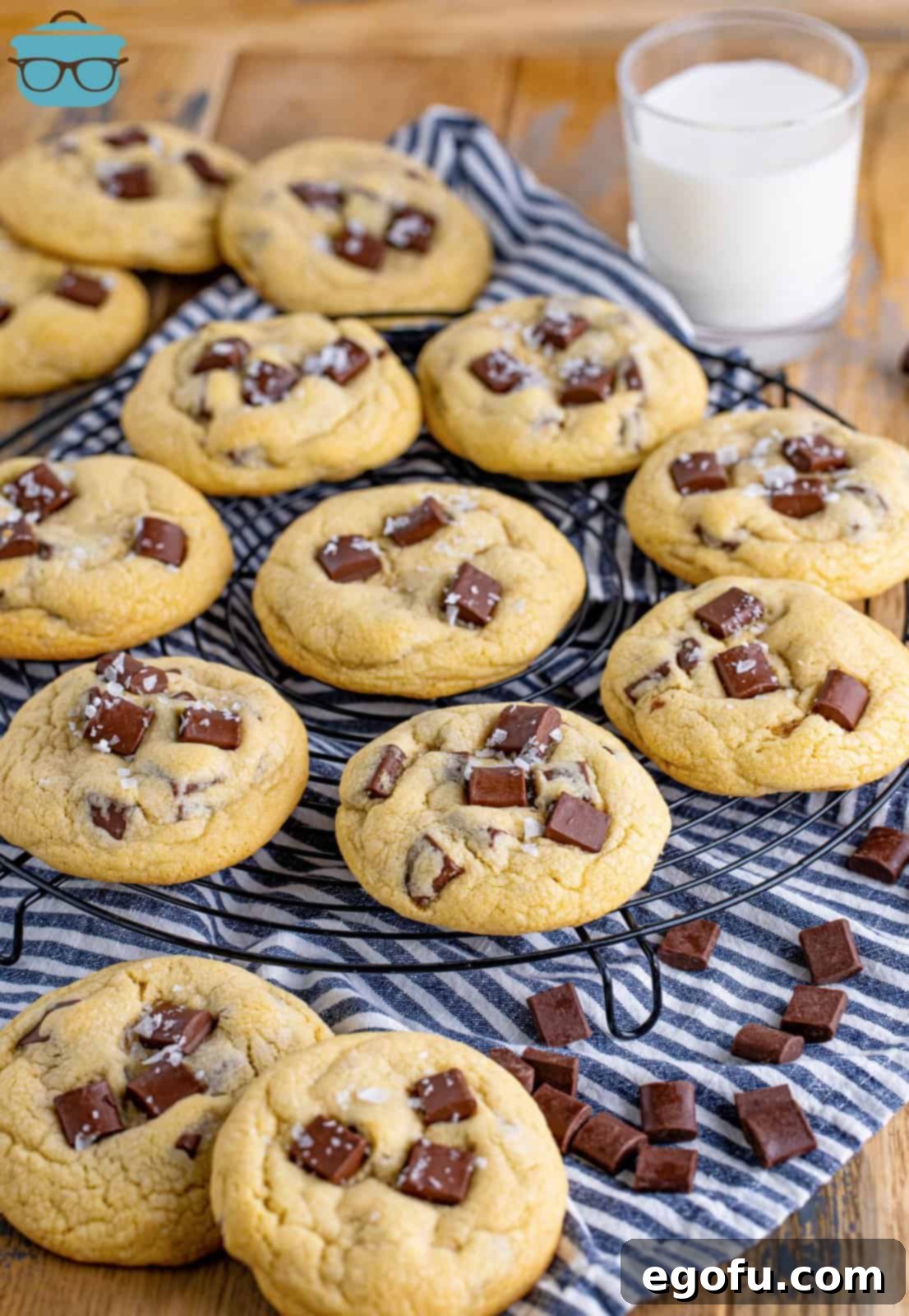 A beautiful array of freshly baked homemade Chocolate Chunk Cookies, garnished with a sprinkle of flaky sea salt, cooling on a wire rack placed over a kitchen towel, showcasing their golden-brown edges and melted chocolate centers.