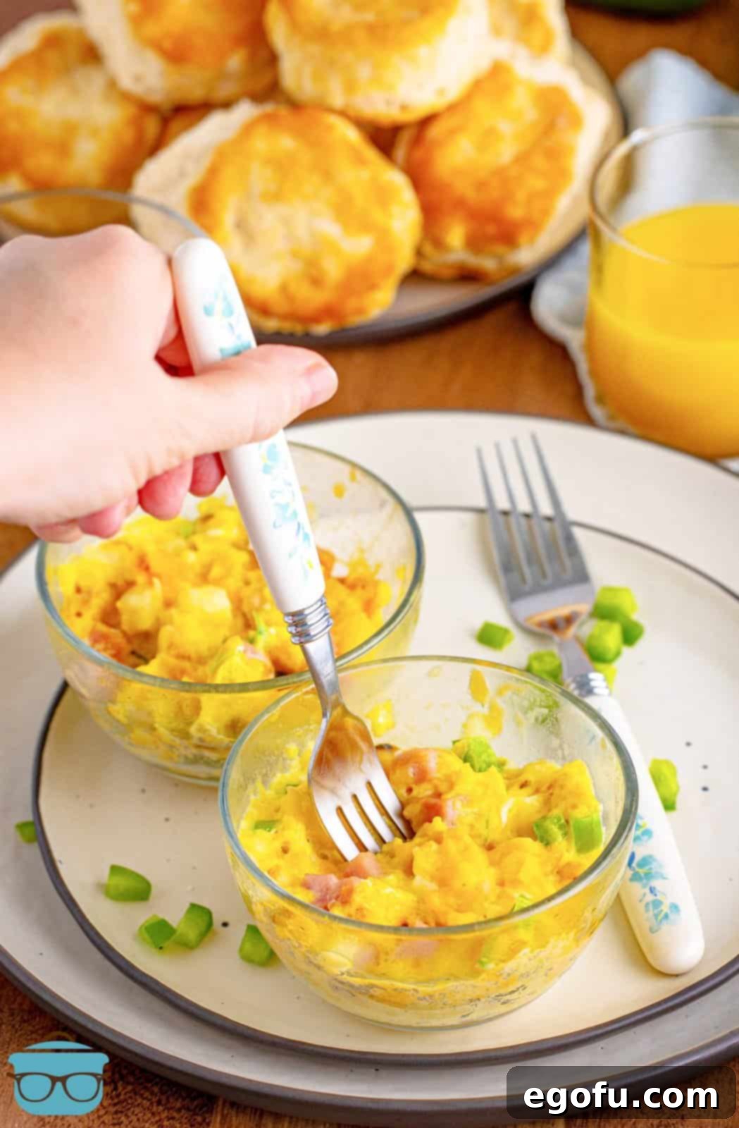 A fork getting a bite from a Microwave Scrambled Eggs Cup on a plate, showcasing its fluffy texture and delicious add-ins.