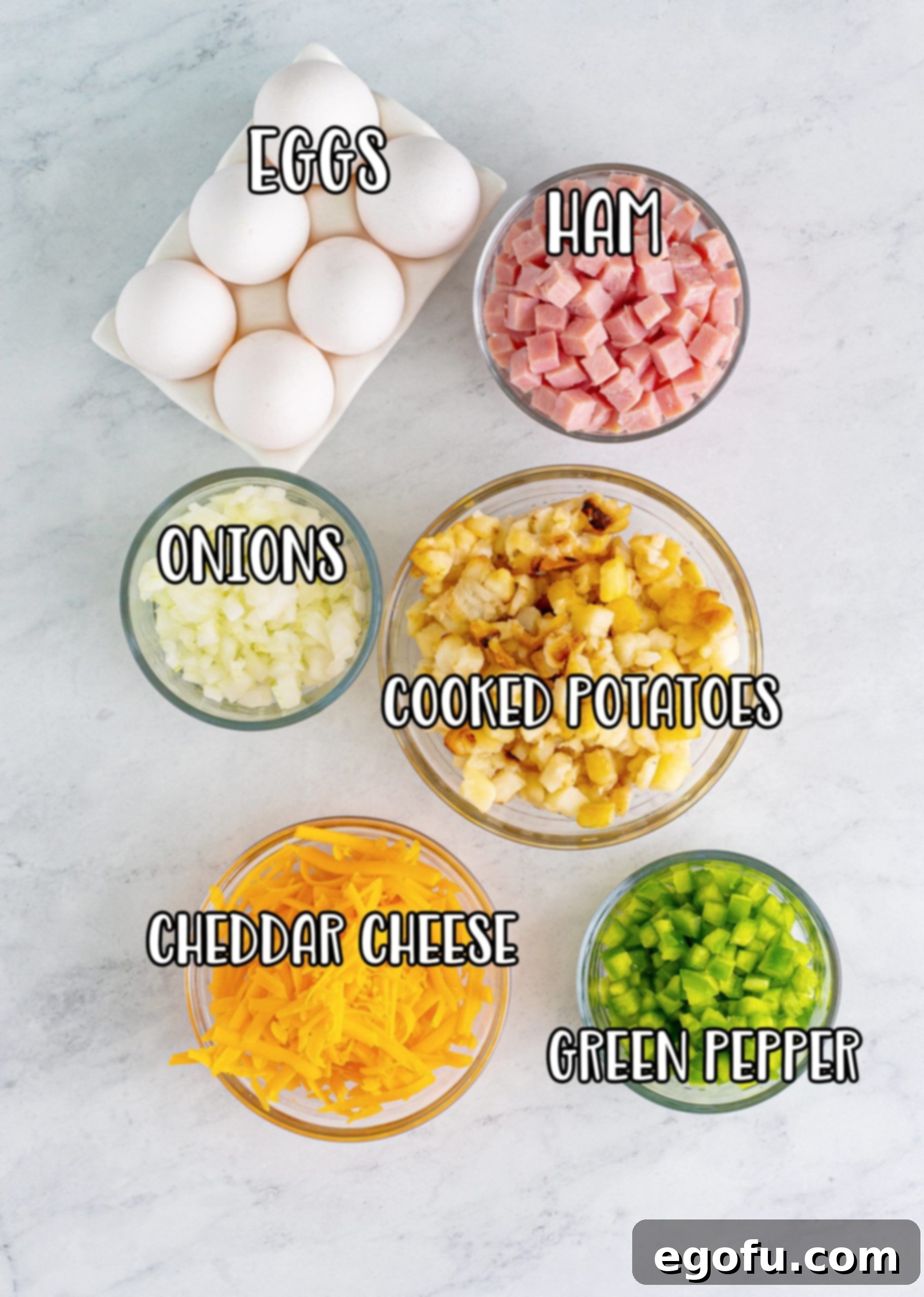 A vibrant flat lay of all the fresh ingredients needed for Microwave Scrambled Eggs Cup: eggs, ham, potatoes, shredded cheese, green peppers, and diced onions.