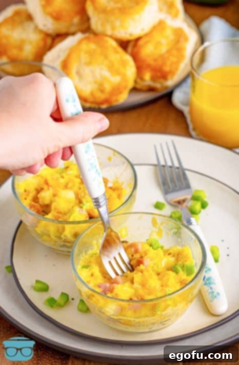 A fork getting a bite from a Microwave Scrambled Eggs Cup on a plate, showing the final cooked product.