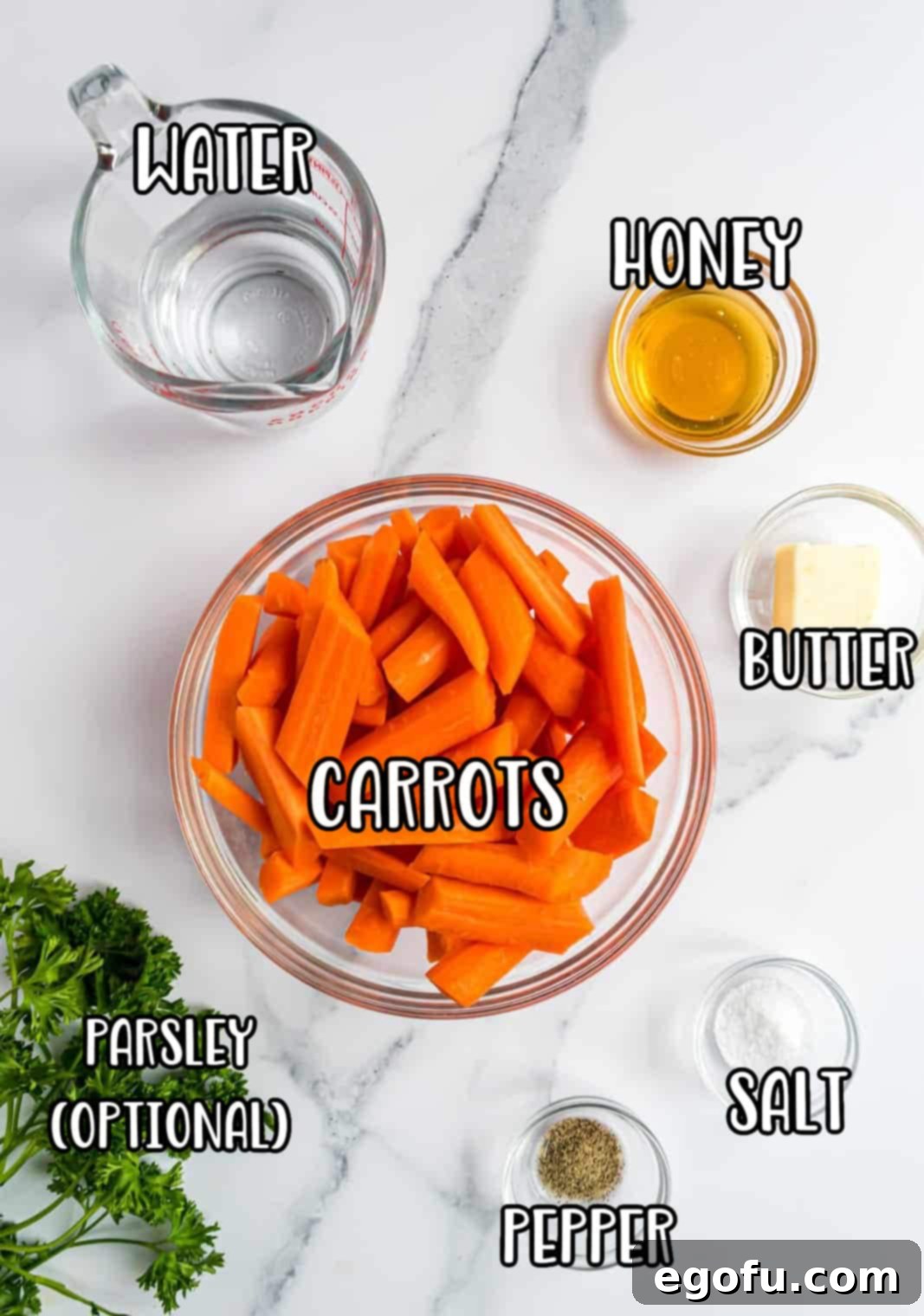 A flat lay photograph displaying all the ingredients needed for Honey Glazed Carrots: fresh carrots, salt, pepper, a jar of honey, a stick of butter, fresh parsley, and a glass of water.