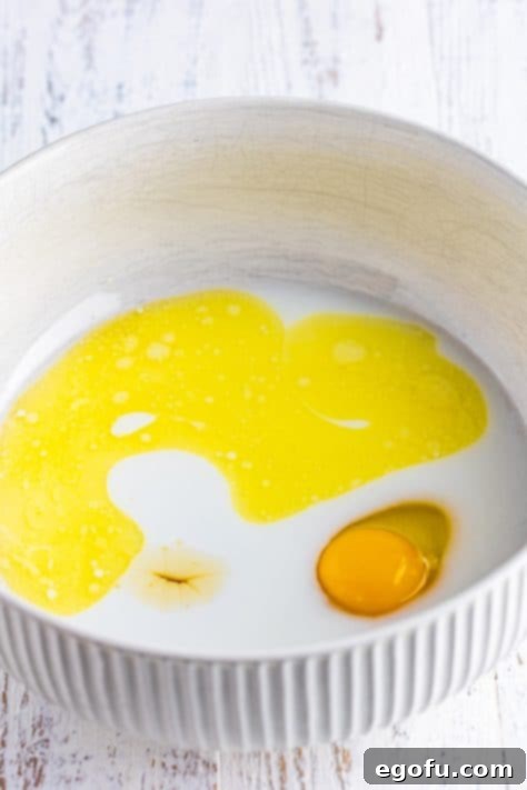 Golden Corn Muffins 9 A mixing bowl with honey, egg, melted butter, milk, and water.