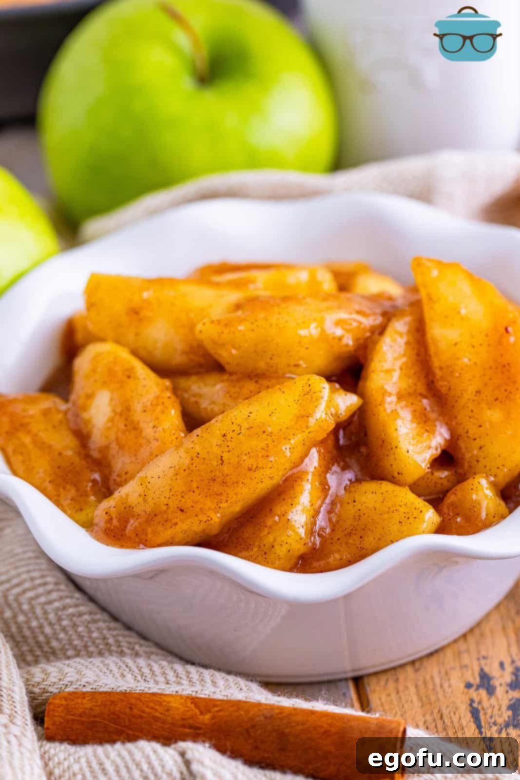 A charming, curly white bowl filled to the brim with warm, glistening Southern Fried Apples, ready to be enjoyed.