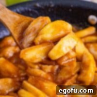 Fried apples in a skillet with a wooden spoon.