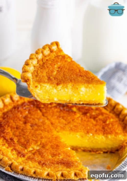 A slice of Buttermilk Pie being held above the rest of the pie.