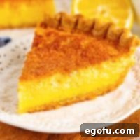A slice of Buttermilk Pie on a white dessert plate, with a slightly golden crust and creamy filling.