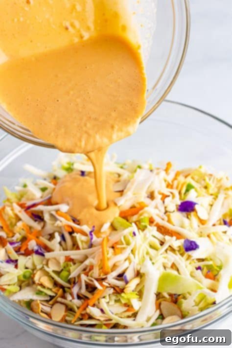 Homemade dressing being poured over the Asian slaw mix.