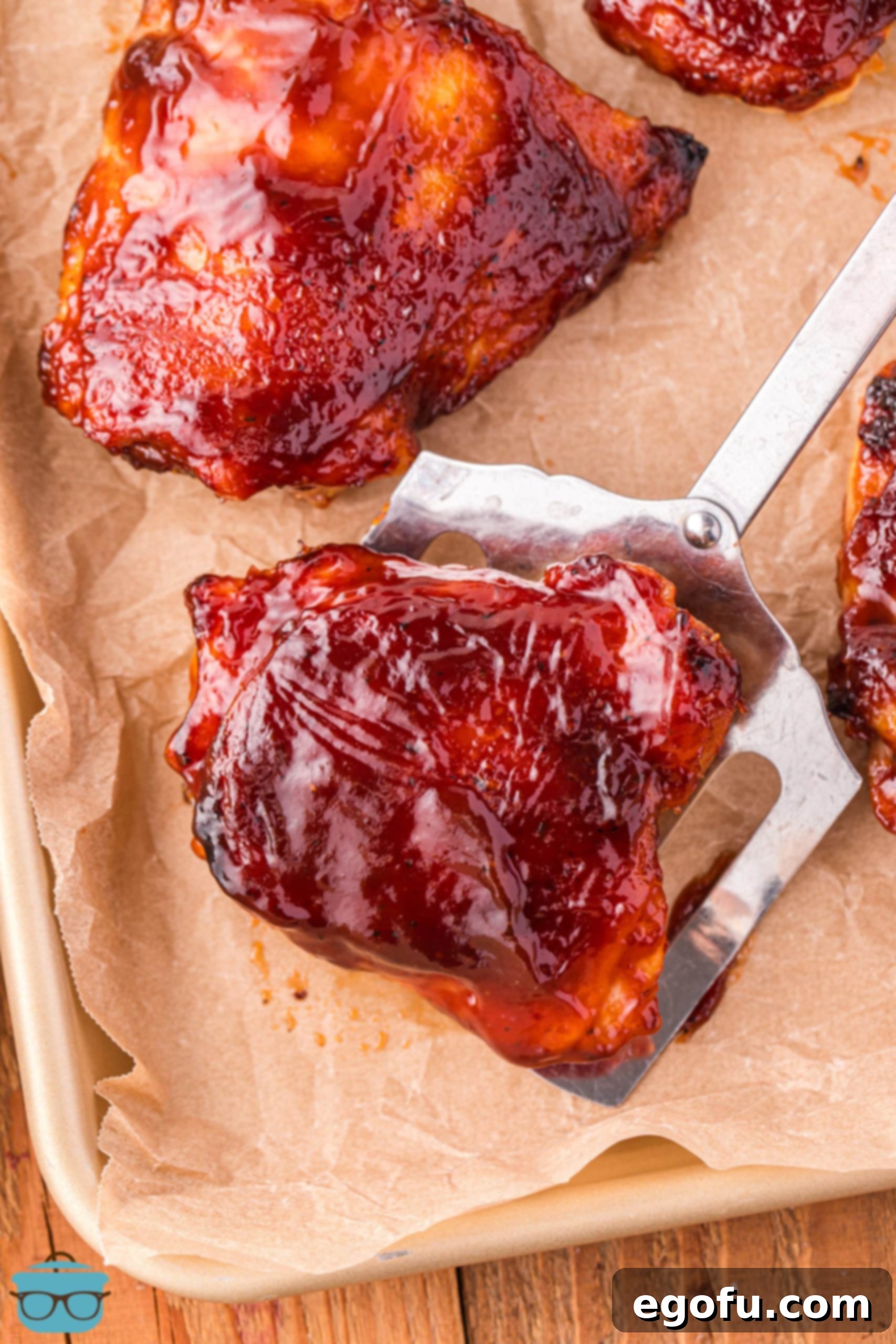 Smoky Barbecue Roasted Chicken Thighs 5 A spatula holding a large BBQ Baked Chicken Thighs.