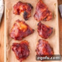 Smoky Barbecue Roasted Chicken Thighs 6 A sheet pan with a few baked chicken thighs covered in bbq sauce.