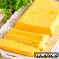 A partially sliced block of Homemade Velveeta Cheese, showcasing its smooth texture.