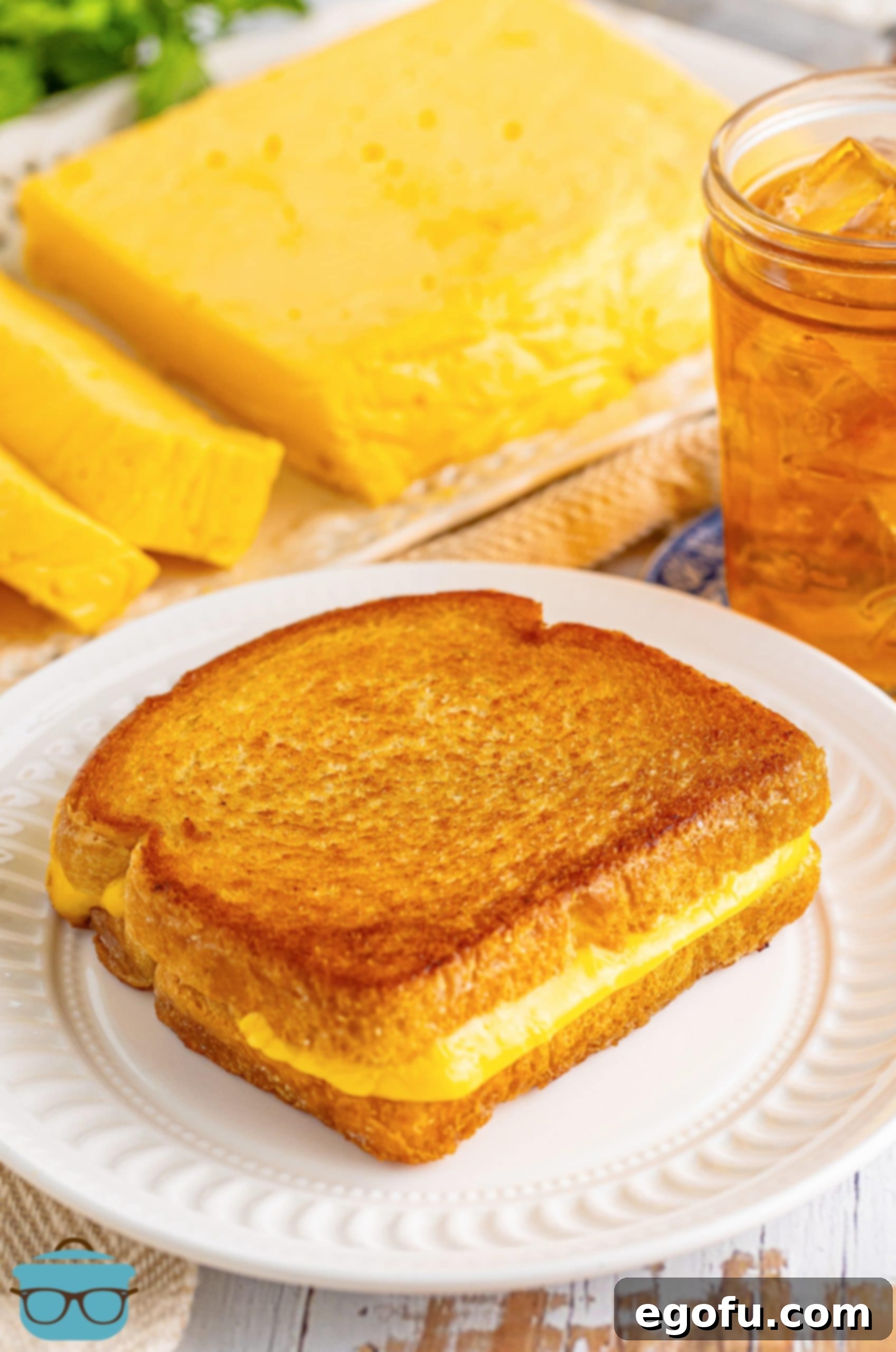 A perfectly golden brown grilled cheese sandwich, oozing with creamy Homemade Velveeta, served on a white plate with a side of chips.