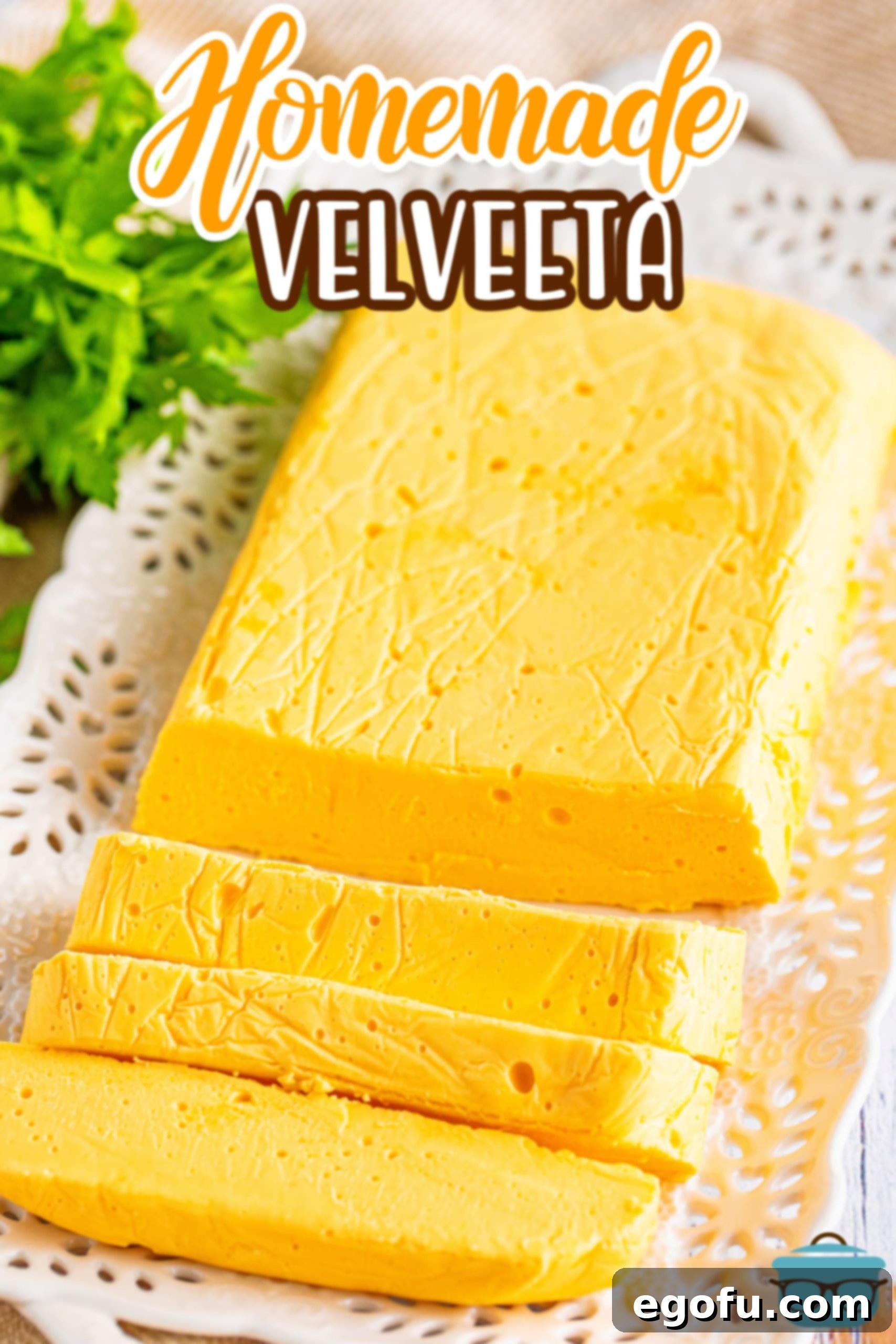 A large, golden-orange block of Homemade Velveeta cheese, with a few rustic chunks already sliced off, highlighting its creamy interior.