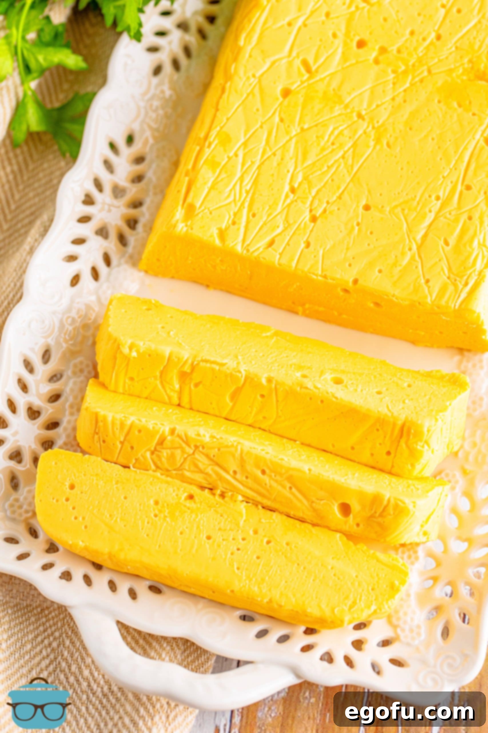 A top-down view of a firm block of Homemade Velveeta cheese, with several neatly cut chunks, showing its consistent and creamy texture.