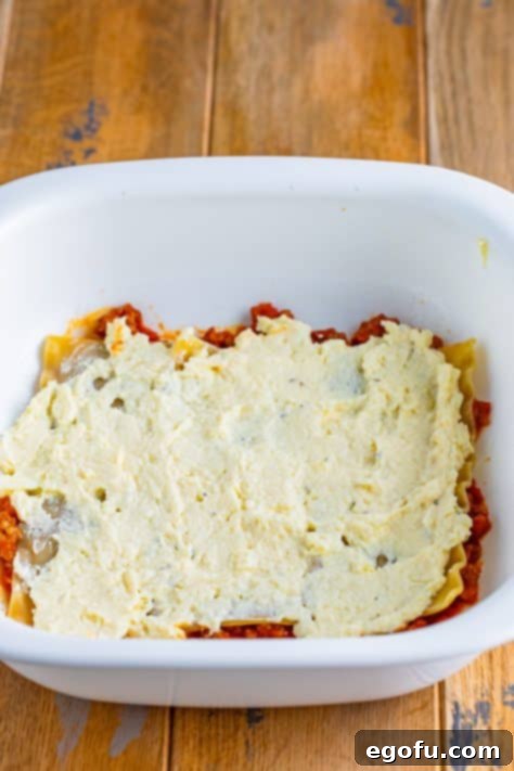 Cozy Lasagna Dinner for Two 19 Ricotta cheese mixture on top of noodles and sauce in a baking dish.