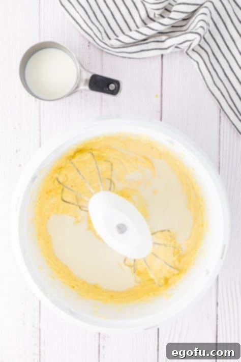 Warm milk being added gradually to a cake batter.