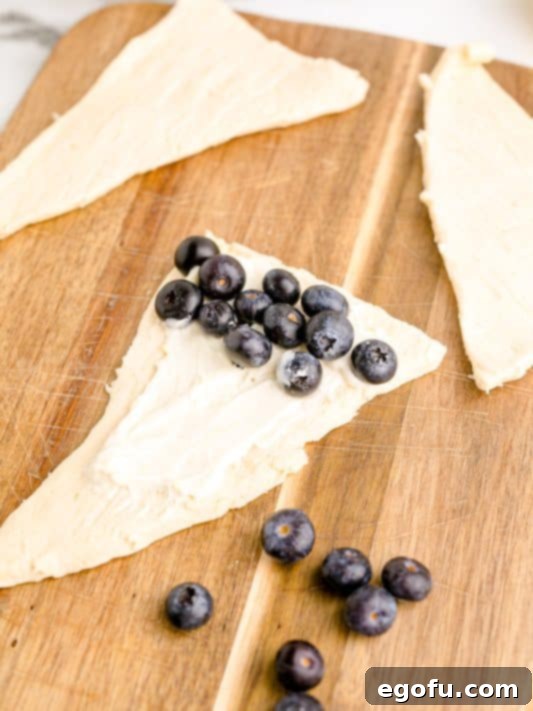 Blueberries and cheesecake filling on a piece of crescent roll dough.